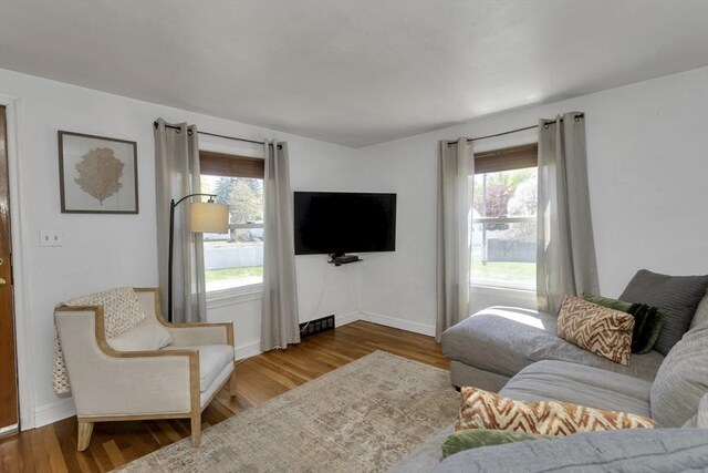 living room featuring baseboards, visible vents, a wealth of natural light, and wood finished floors