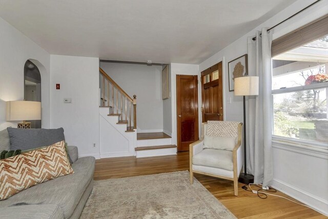 living room with baseboards, stairs, wood finished floors, and arched walkways