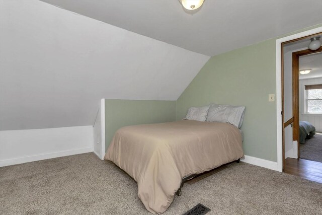 bedroom featuring baseboards, vaulted ceiling, and light carpet