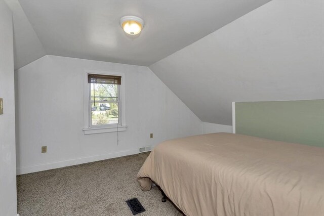 bedroom with carpet floors, baseboards, vaulted ceiling, and visible vents