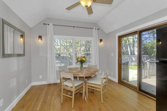 dining room with a ceiling fan, baseboards, vaulted ceiling, and light wood finished floors
