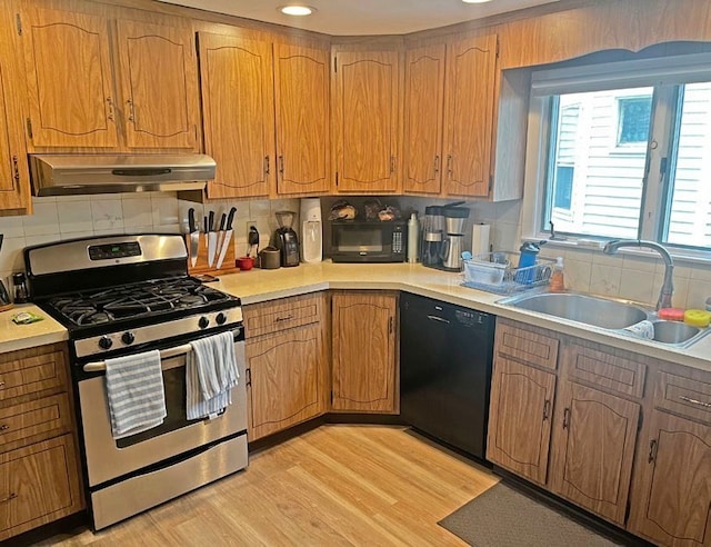 kitchen featuring black appliances, backsplash, light hardwood / wood-style floors, and sink