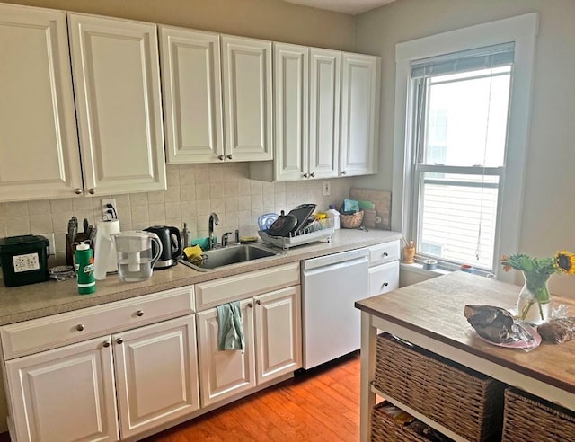 kitchen featuring light wood-type flooring, backsplash, sink, dishwasher, and white cabinetry