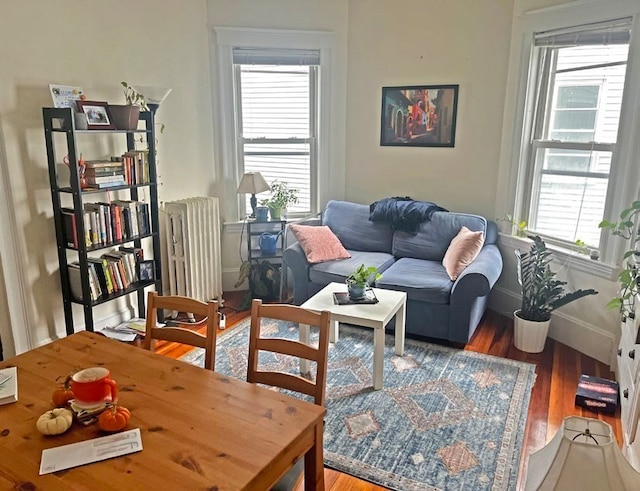 sitting room featuring radiator heating unit, a healthy amount of sunlight, and wood-type flooring