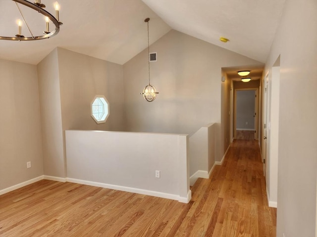 interior space featuring an inviting chandelier, vaulted ceiling, baseboards, and light wood finished floors