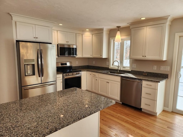 kitchen featuring hanging light fixtures, stainless steel appliances, light wood-type flooring, a sink, and recessed lighting