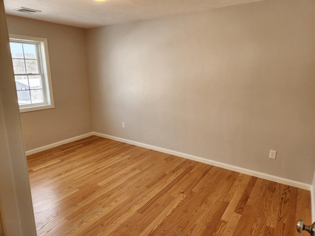 spare room with light wood-style flooring, visible vents, and baseboards