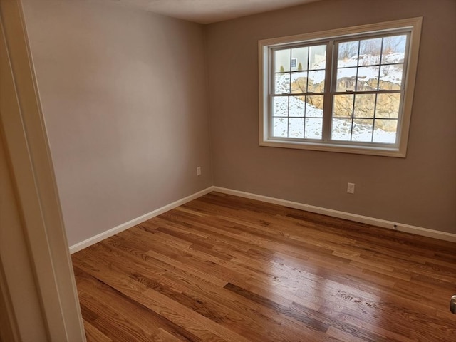 spare room featuring baseboards and wood finished floors