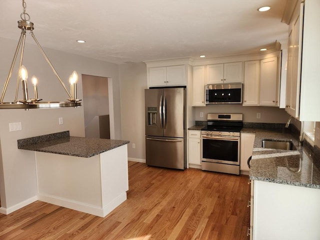 kitchen with recessed lighting, stainless steel appliances, a sink, light wood-style floors, and dark stone counters