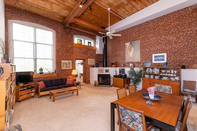 dining area featuring a healthy amount of sunlight, wooden ceiling, a ceiling fan, and brick wall