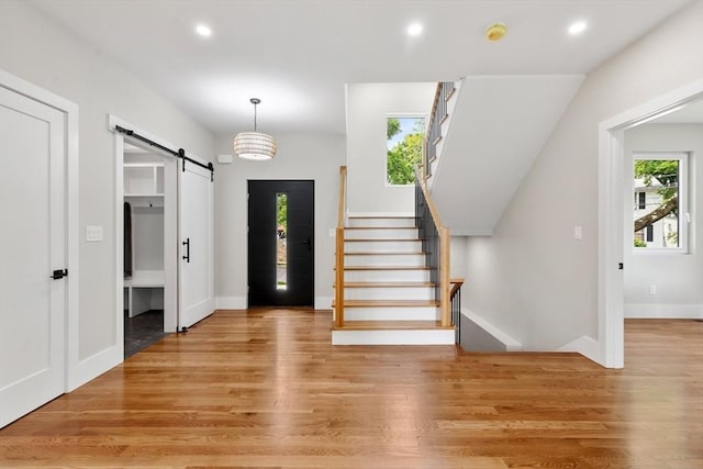 66 Upham St, Newton, MA 02465 - entrance foyer with a barn door, light wood finished floors, recessed lighting, stairway, and baseboards