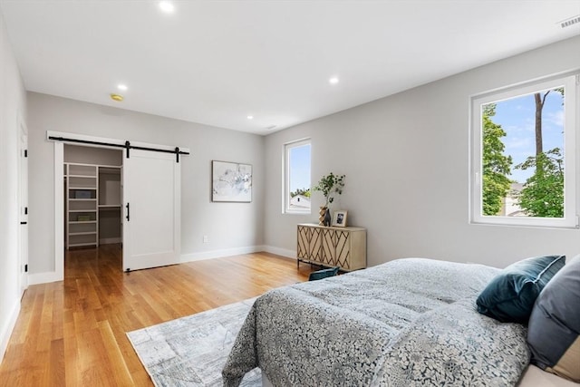 66 Upham St, Newton, MA 02465 - bedroom featuring multiple windows, a barn door, light wood-type flooring, recessed lighting, and a walk in closet