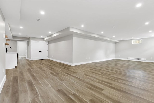 66 Upham St, Newton, MA 02465 - unfurnished living room featuring baseboard heating, light wood-type flooring, recessed lighting, baseboards, and a sink