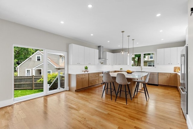 66 Upham St, Newton, MA 02465 - kitchen with wall chimney range hood, a breakfast bar area, stainless steel appliances, healthy amount of natural light, and recessed lighting