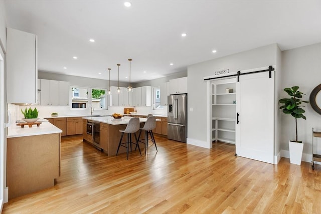 66 Upham St, Newton, MA 02465 - kitchen featuring stainless steel fridge, a barn door, a kitchen island, light countertops, and a kitchen bar