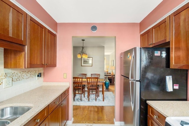 17 Angela Ln Unit 17, Watertown, MA 02472 - kitchen featuring light wood finished floors, brown cabinetry, freestanding refrigerator, tasteful backsplash, and light stone countertops