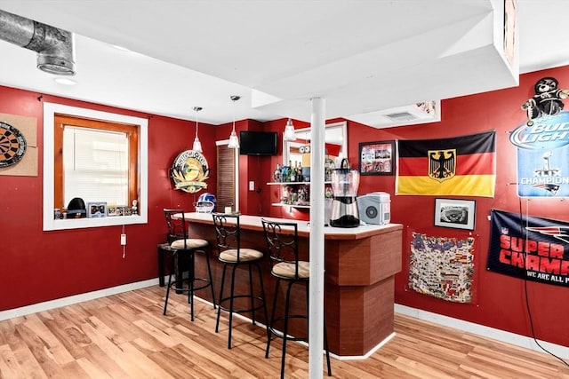 bar with hardwood / wood-style flooring and decorative light fixtures