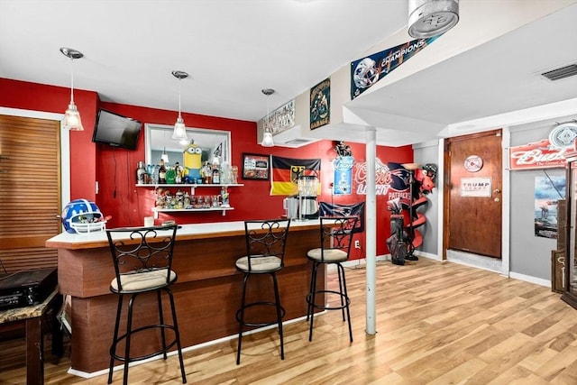 bar with hardwood / wood-style floors and hanging light fixtures