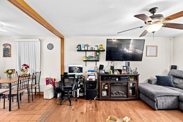 living room featuring hardwood / wood-style flooring, ceiling fan, and a textured ceiling