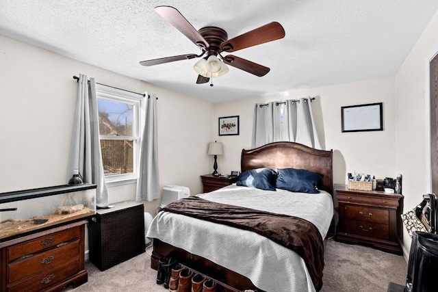 bedroom featuring ceiling fan, light colored carpet, and a textured ceiling