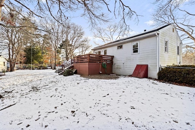 snow covered back of property featuring a deck