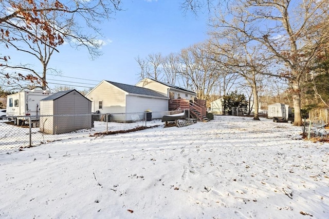 snow covered back of property featuring a storage unit