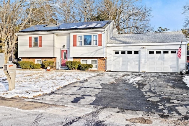 raised ranch featuring a garage and solar panels