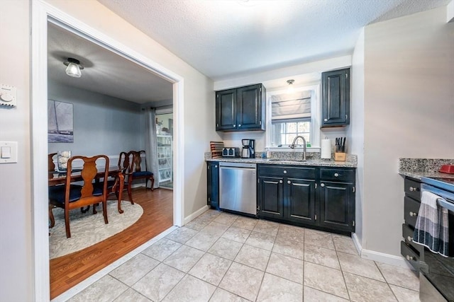 kitchen with a sink, light tile patterned floors, baseboards, dishwasher, and light stone countertops