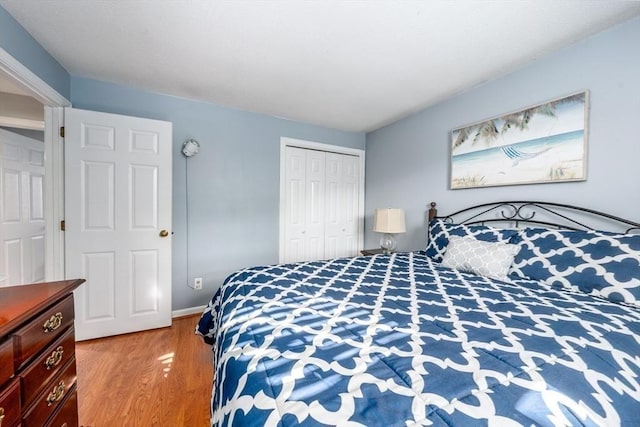 bedroom with a closet, baseboards, and wood finished floors