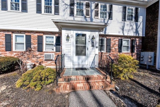 property entrance featuring brick siding and a wall mounted AC