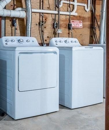 washroom featuring wooden walls, laundry area, and washer and clothes dryer