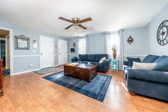 living area with baseboards, light wood-style flooring, and a ceiling fan