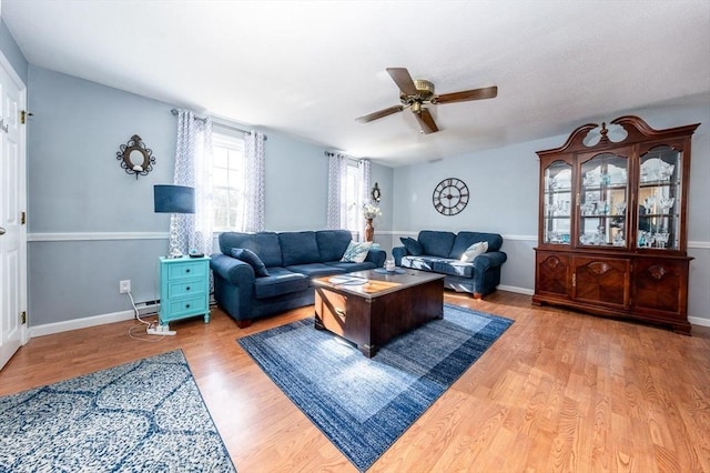 living room with wood finished floors, baseboards, baseboard heating, and ceiling fan