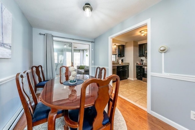 dining room featuring light wood finished floors, baseboards, and baseboard heating