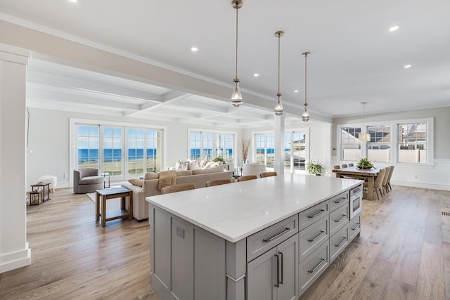 kitchen with decorative light fixtures, light hardwood / wood-style floors, light stone counters, and gray cabinetry