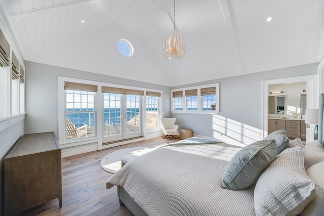 bedroom featuring a notable chandelier, high vaulted ceiling, wood-type flooring, connected bathroom, and a water view