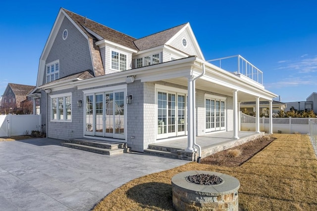 rear view of house with a balcony, a fire pit, french doors, and a patio