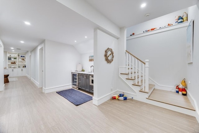 foyer with sink, vaulted ceiling, beverage cooler, and light hardwood / wood-style floors