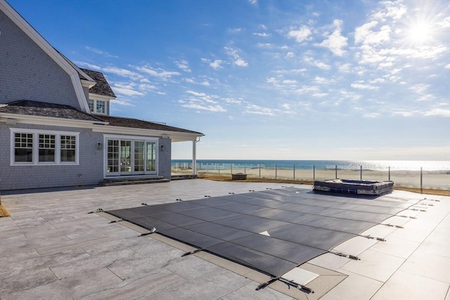 view of pool with a water view, a hot tub, and a patio