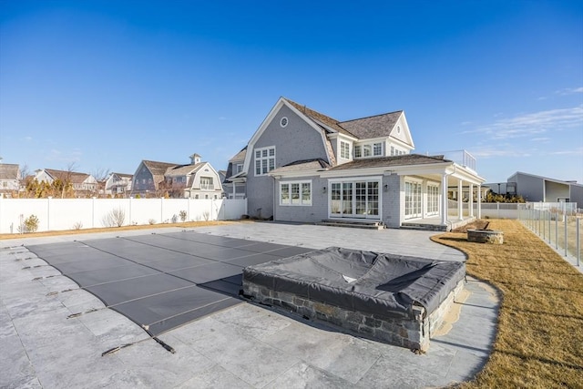 rear view of property featuring a balcony, a patio area, and a covered pool