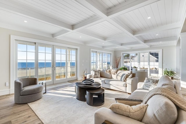 living room featuring beamed ceiling, a view of the beach, a water view, and light wood-type flooring