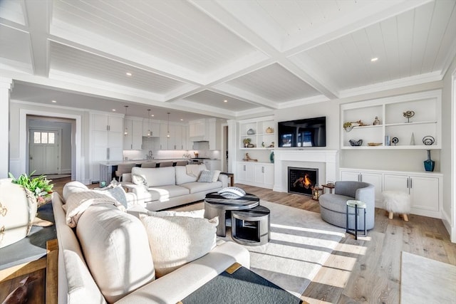 living room featuring beamed ceiling, ornamental molding, light hardwood / wood-style flooring, and built in shelves