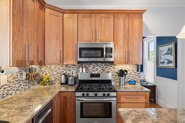 37 Devereux St, Marblehead, MA 01945 - kitchen featuring appliances with stainless steel finishes, light stone countertops, brown cabinetry, decorative backsplash, and ornamental molding
