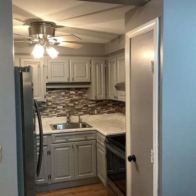 kitchen with tasteful backsplash, sink, stainless steel fridge, and range with electric cooktop