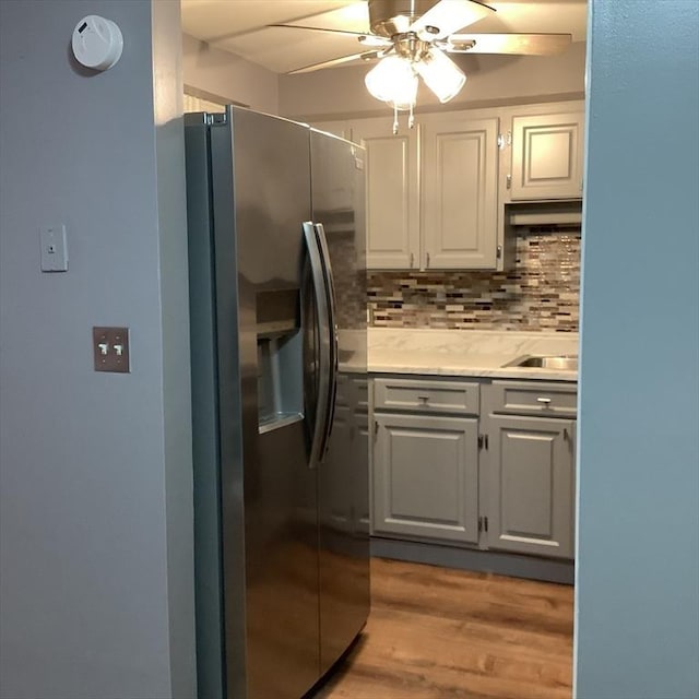 kitchen with ceiling fan, backsplash, stainless steel refrigerator with ice dispenser, white cabinets, and light wood-type flooring