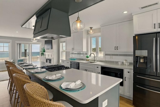 1091 Winthrop Ave, Revere, MA 02151 - kitchen featuring refrigerator with ice dispenser, dishwasher, a kitchen island, a kitchen breakfast bar, and recessed lighting