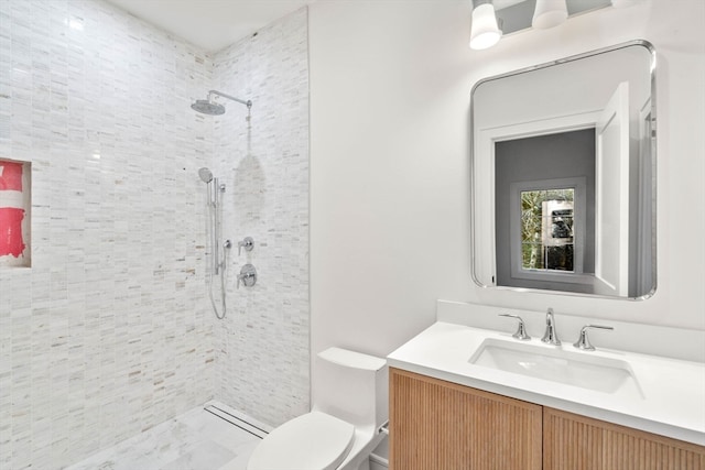 full bath featuring tiled shower, vanity, and toilet