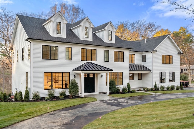 view of front of house with a shingled roof, metal roof, aphalt driveway, a standing seam roof, and a front yard