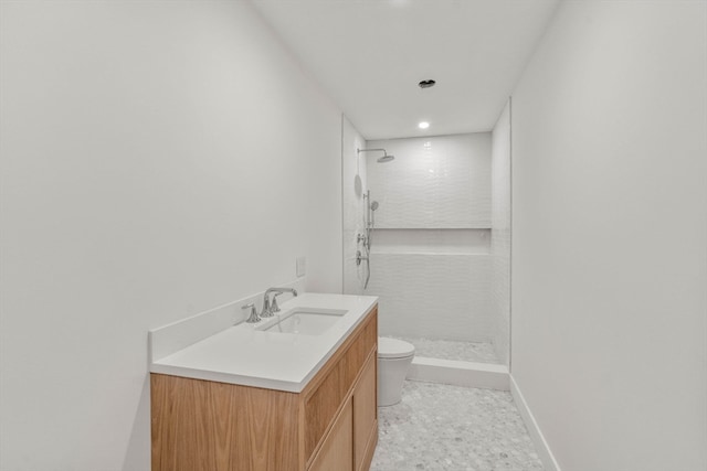 bathroom with a stall shower, vanity, toilet, and baseboards