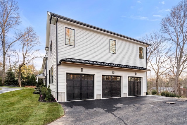 view of side of property with a garage, a standing seam roof, a lawn, and metal roof